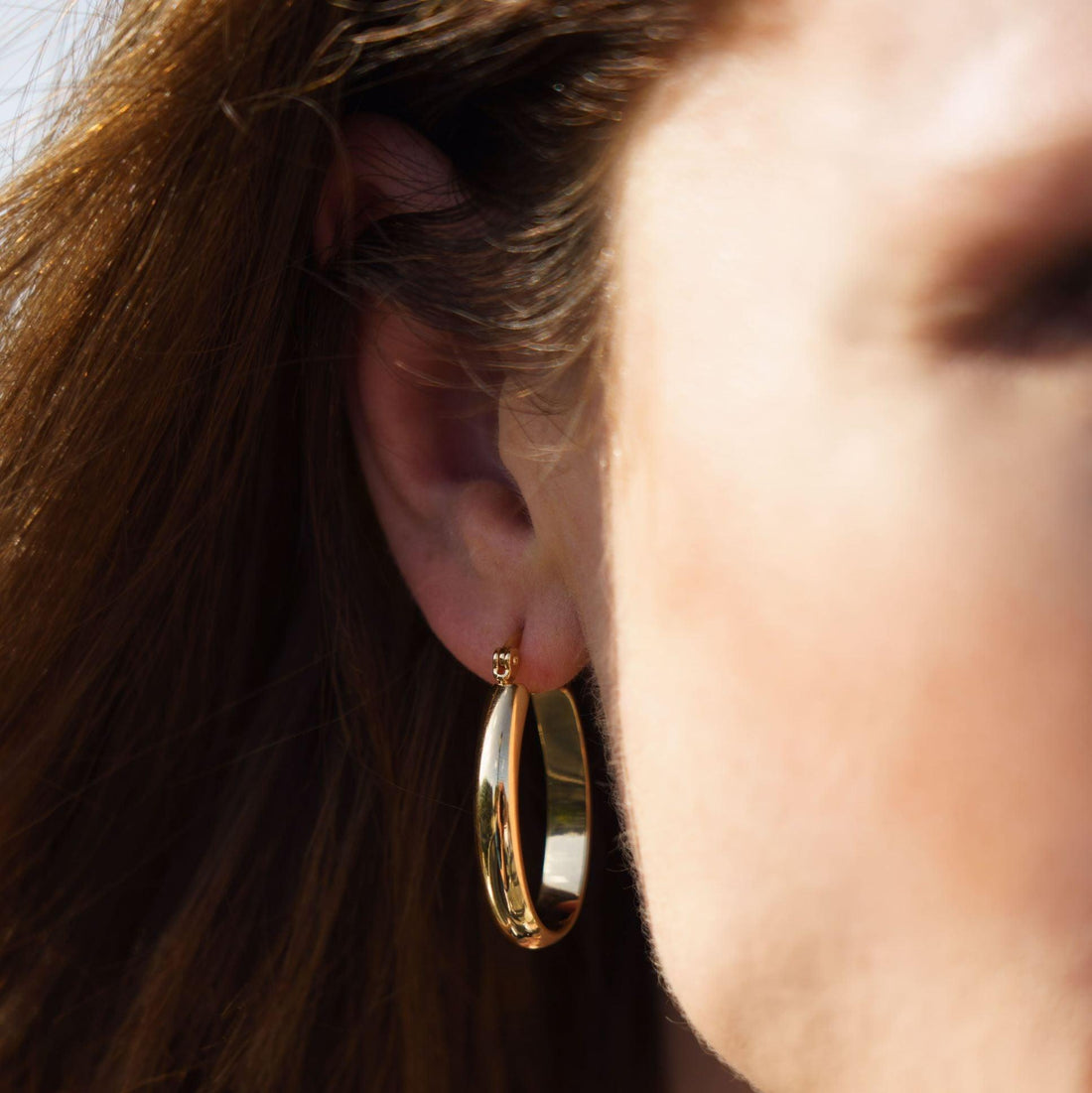 Femme portant les Boucles Laetia, créoles dorées élégantes
