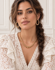 Femme portant les boucles d’oreilles Félix, créoles dorées à boules avec une tenue en dentelle blanche – Jossepo