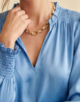 Collier Ginevra en plaqué or porté par une femme avec une blouse bleue élégante – Jossepo