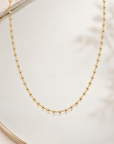 Collier Miromesnil en plaqué or à petites boules dorées, présenté sur un miroir avec reflet, vue d’ensemble
