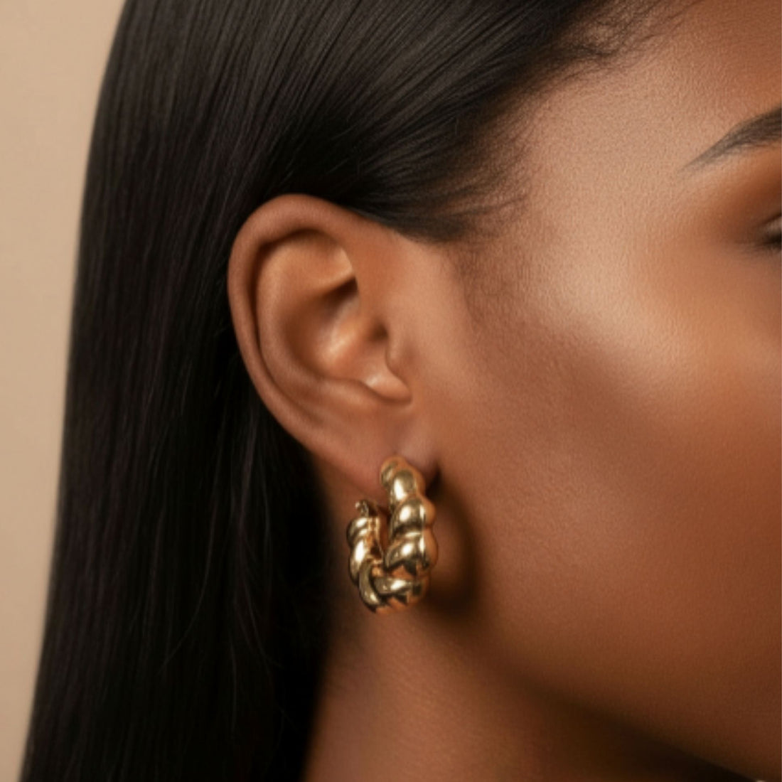 Modèle portant des boucles d’oreilles dorées sculptées en forme d’anneaux épais et entrelacés – Jossepo