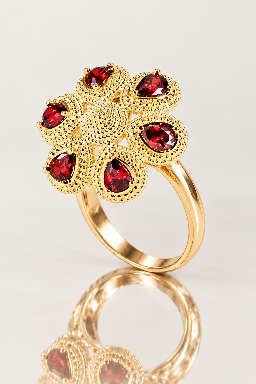 Bague Fergui en plaqué or 18 carats, fleur à six pierres rouges présentée debout sur une surface miroir