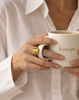 Bague Kléber en plaqué or et pierre verte portée par une femme tenant une tasse – Jossepo