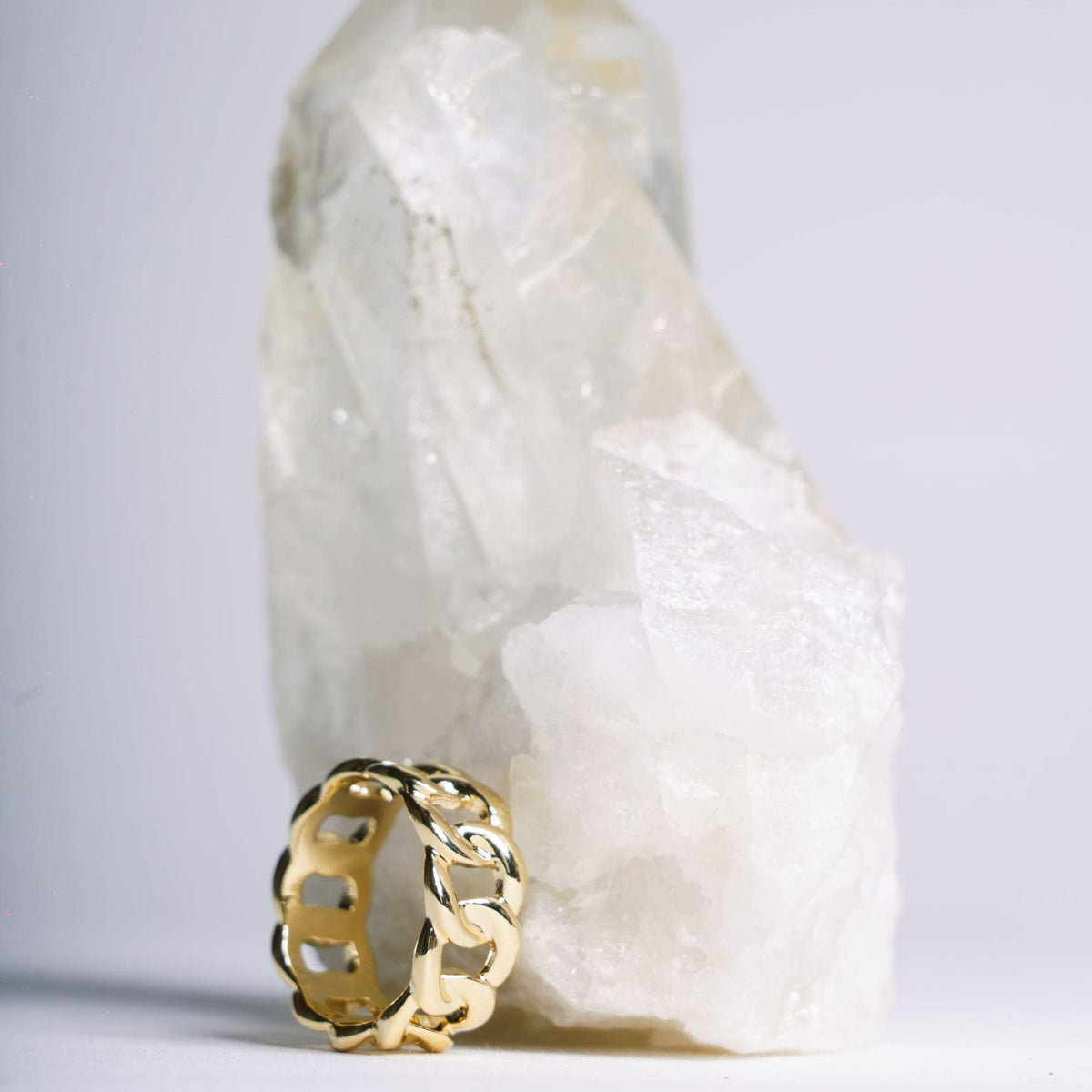 Bague chaîne Mila dorée présentée contre une pierre blanche