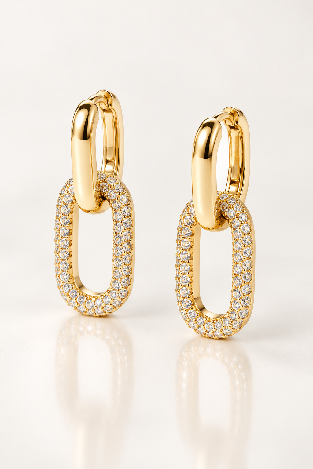 Boucles d’oreilles Cambronne de 22 mm, maillon doré lisse et maillon ovale pavé blanc vus de trois quarts avec reflet miroir.