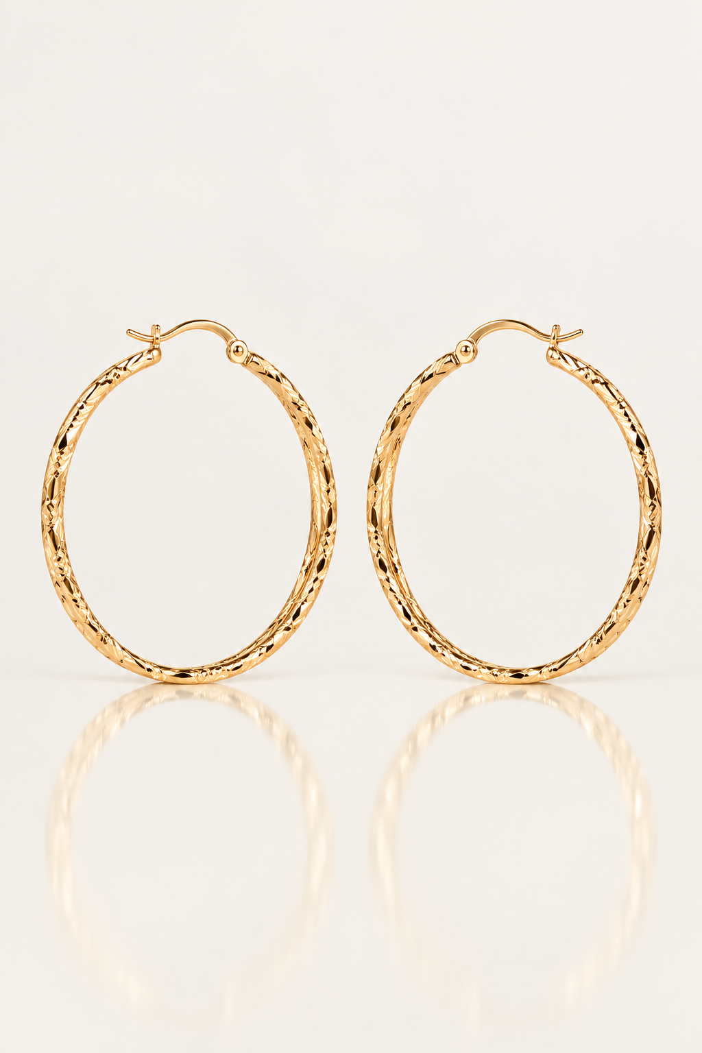 Boucles d’oreilles Courcelles 43 mm en plaqué or, créoles ciselées, paire vue de face sur fond clair avec reflet.