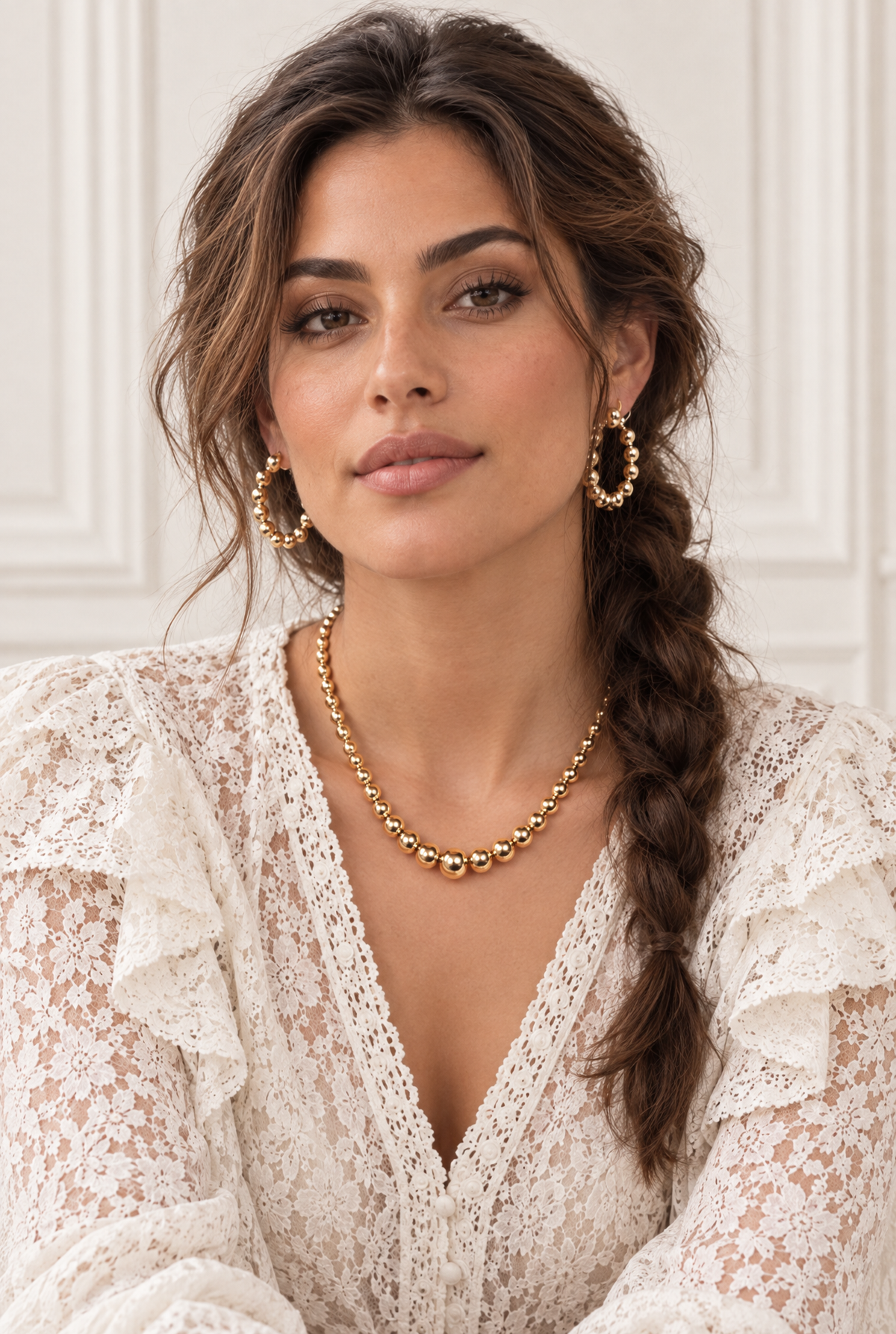 Femme portant les boucles d’oreilles Félix, créoles dorées à boules avec une tenue en dentelle blanche – Jossepo