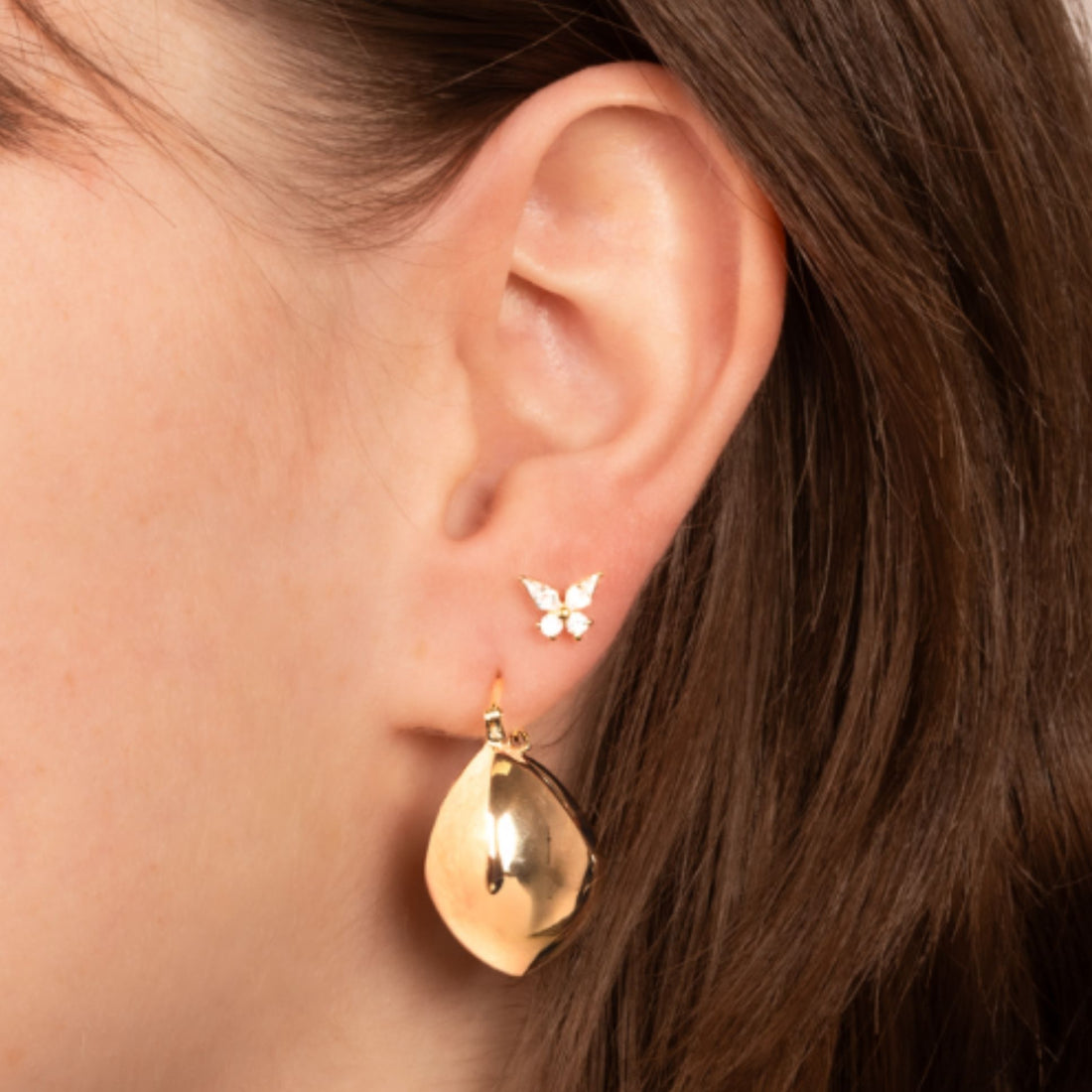 Femme portant des boucles d’oreilles goutte en plaqué or 18 carats avec un mini clou papillon doré – Jossepo