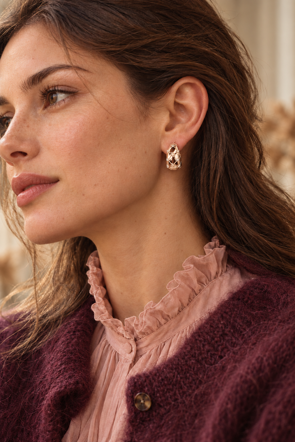 Créoles Marceau dorées portées avec une maille prune et une blouse rose à col victorien.