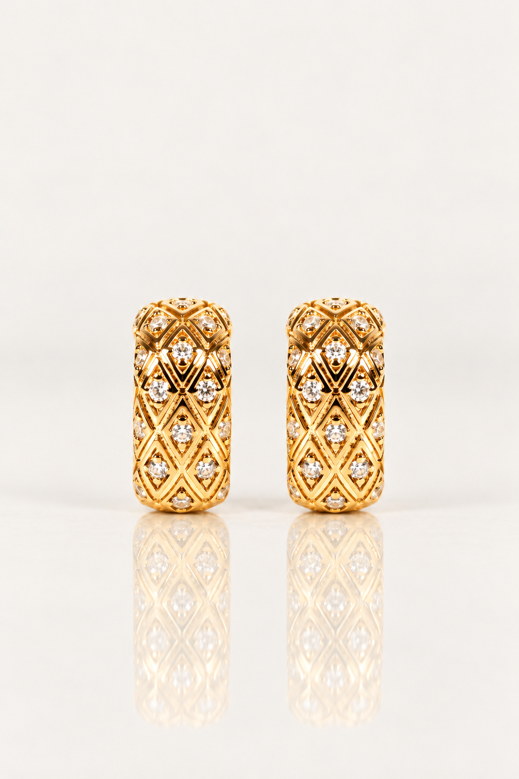Boucles d’oreilles Sèvres 16 mm en plaqué or, paire de petites créoles à motifs losanges vue de face sur fond clair avec reflet.