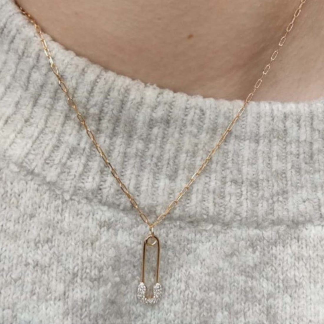 Collier pendentif épingle dorée avec strass en plaqué or 18 carats porté sur un pull clair