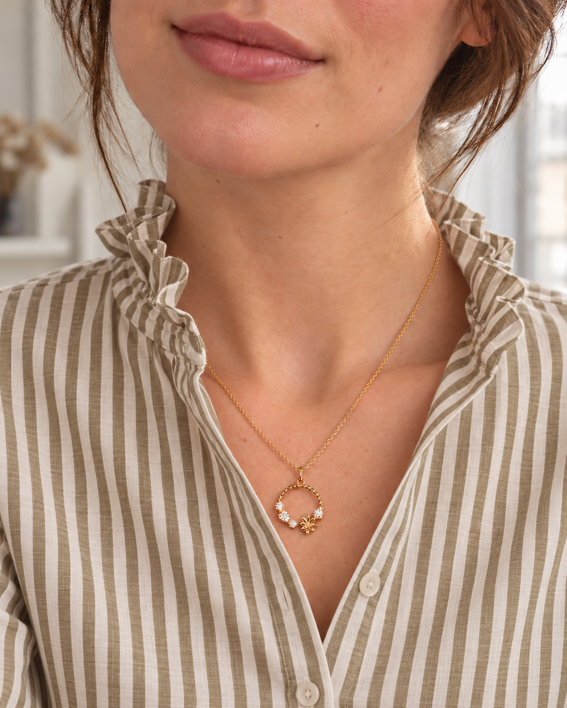 Collier Solférino au pendentif cercle floral porté avec une chemise à rayures kaki et beige et col volanté, vue rapprochée dans un appartement parisien