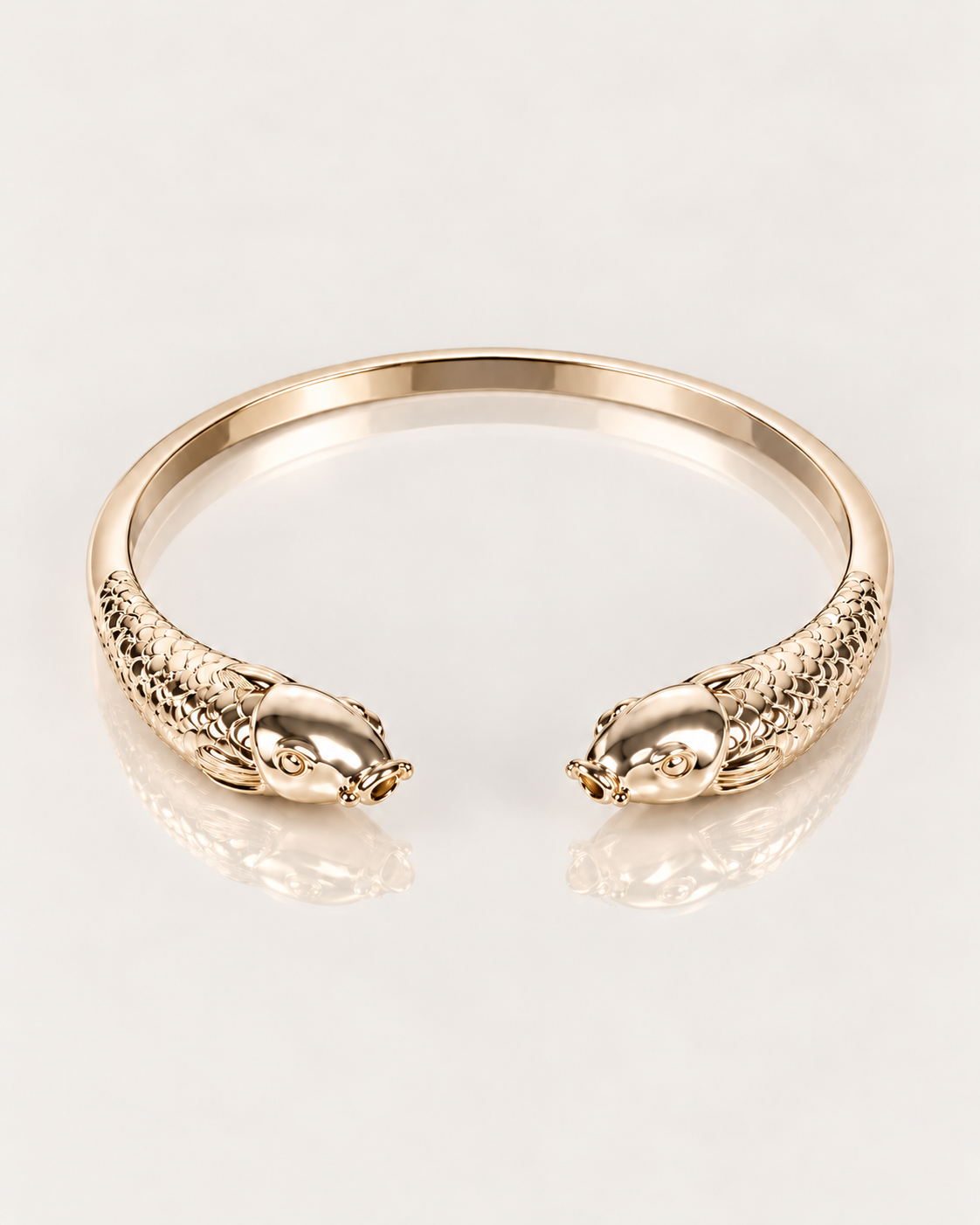 Bracelet jonc Poisson en plaqué or 18 carats, vue du dessus des deux têtes de poisson et des écailles sculptées sur une surface miroir