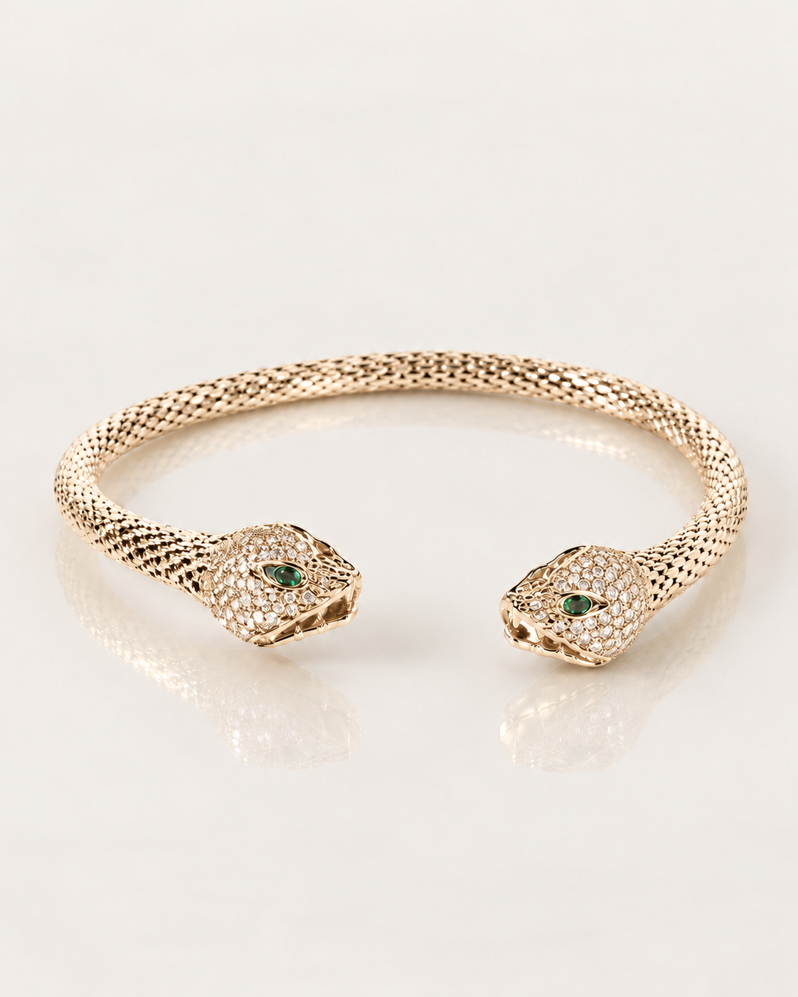 Bracelet jonc Serpent Zirconiums en plaqué or, corps texturé et têtes pavées de zirconiums, vue du dessus sur fond clair avec reflet